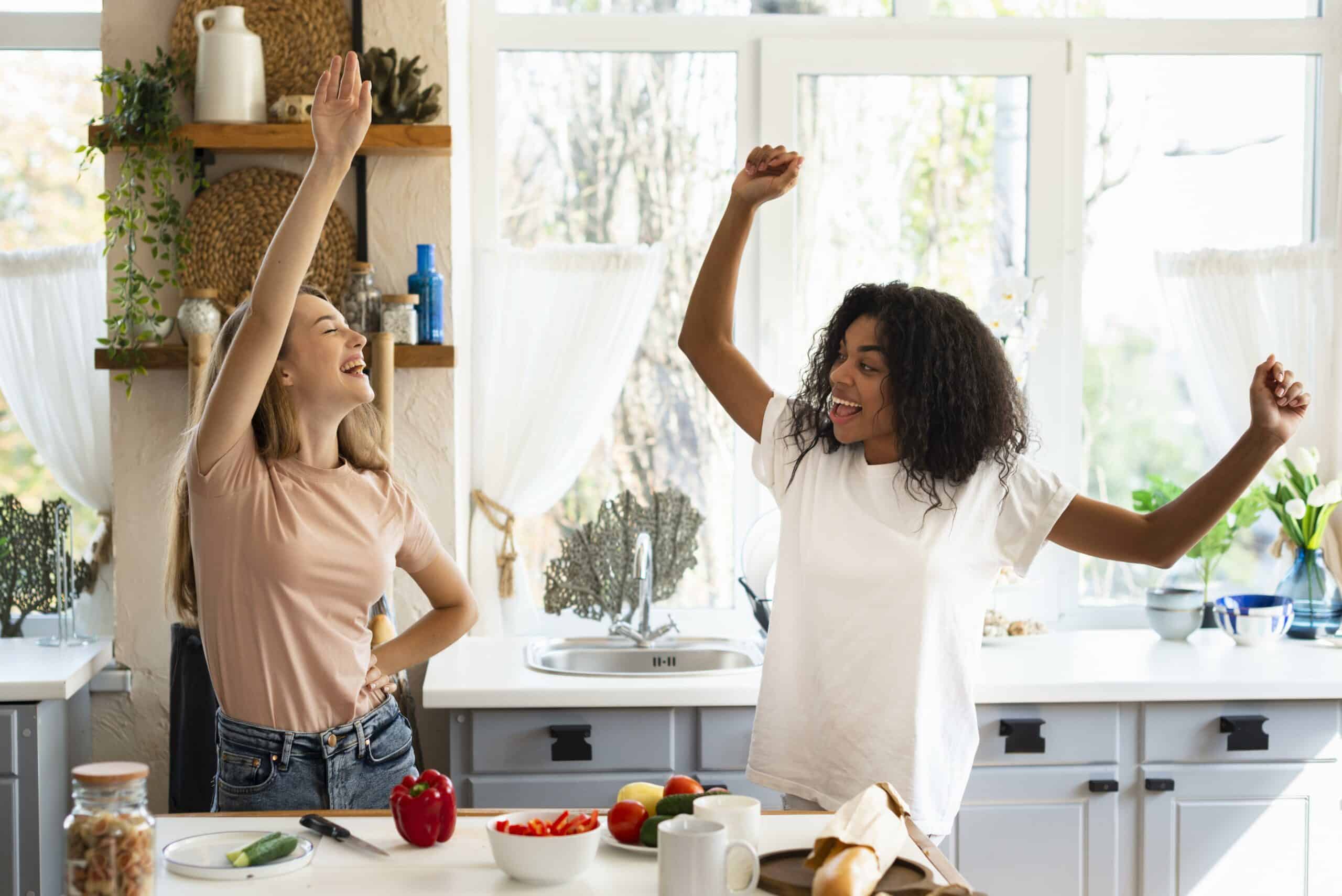 two-female-friends-dancing-while-cooking-kitchen